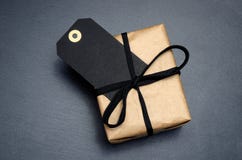 Black Background And Price Label. Black Friday. Sales Concept. Copy Space. Black Paper Label And Gift Box From Recycled Brown Pape Royalty Free Stock Photos Black Background And Price Label. Black Friday. Sales Concept. Copy Space. Black Paper Label And Gift Box From Recycled Brown Pape Royalty Free Stock Photos
