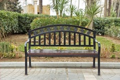 Black iron chair . Black bench on the street . Bench in Park on a background of brick green tree royalty free stock images Black iron chair . Black bench on the street . Bench in Park on a background of brick green tree royalty free stock images
