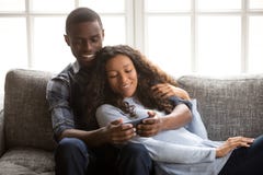 Black couple in love on couch using mobile phone stock photography Black couple in love on couch using mobile phone stock photography