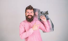 Black friday concept. Guy shopping and shows thumbs up gesture. Man with beard and mustache carries bunch of shopping stock photography Black friday concept. Guy shopping and shows thumbs up gesture. Man with beard and mustache carries bunch of shopping stock photography