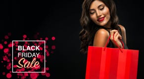 Black friday sale concept. Shopping woman holding red bag isolated on dark background in holiday stock images Black friday sale concept. Shopping woman holding red bag isolated on dark background in holiday stock images
