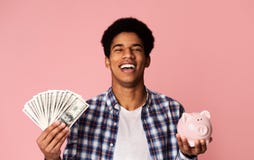 Black Guy Holding Money And Piggybank On Pink Background Royalty Free Stock Photo