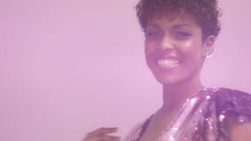 Black mixed race woman with short haircut and curly natural hair wears sequin sparkly dress in pink