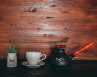 Black and Orange Turkish Coffee Pot on Table Near Cup and Saucer Royalty Free Stock Image Black and Orange Turkish Coffee Pot on Table Near Cup and Saucer Royalty Free Stock Image