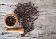 Black pepper in grains with a wooden mortar on a rustic table royalty free stock images Black pepper in grains with a wooden mortar on a rustic table royalty free stock images