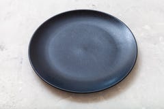 Black plate on gray concrete surface. One black plate on gray concrete surface Royalty Free Stock Photo Black plate on gray concrete surface. One black plate on gray concrete surface Royalty Free Stock Photo