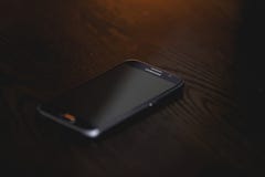 Black Samsung Smartphone at Brown Wooden Surface Stock Image Black Samsung Smartphone at Brown Wooden Surface Stock Image