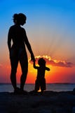 Black silhouette of mother, baby son walk by sea beach stock images Black silhouette of mother, baby son walk by sea beach stock images