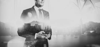 Black white photo of businessman holding smartphone. Double exposure, city on the background. Wide stock photography Black white photo of businessman holding smartphone. Double exposure, city on the background. Wide stock photography