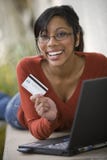 Black woman using credit card and laptop outside