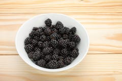 Blackberries in a white bowl on wooden table stock images Blackberries in a white bowl on wooden table stock images