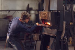 Blaksmith novo que trabalha em uma oficina metalúrgica imagem de stock Blaksmith novo que trabalha em uma oficina metalúrgica imagem de stock