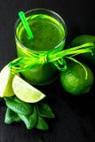 Blandad grön smoothie med ingredienser på den svarta tabellen royaltyfri bild Blandad grön smoothie med ingredienser på den svarta tabellen royaltyfri bild