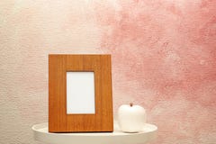 Blank frame and decorative apple figure on table near color wall. Royalty Free Stock Photos Blank frame and decorative apple figure on table near color wall. Royalty Free Stock Photos