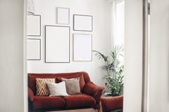 Blank picture frames mockups on white wall. White living room design. View of modern boho, scandi style interior with