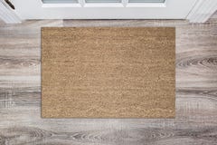 Blank tan colored coir doormat before the white door in the hall. Mat on wooden floor, product Mockup
