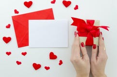 Blank white greeting card with red envelope and gift box in female`s hands. royalty free stock images Blank white greeting card with red envelope and gift box in female`s hands. royalty free stock images