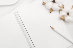 Blank white spiral notebook with pencil, cotton flowers and wooden letter on white bed sheet. stock image Blank white spiral notebook with pencil, cotton flowers and wooden letter on white bed sheet. stock image