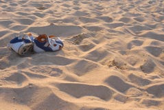 Blau-orange Sandalen auf einem sandigen Ozeanstrand lizenzfreies stockbild Blau-orange Sandalen auf einem sandigen Ozeanstrand lizenzfreies stockbild