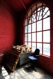 Blauer Stuhl, Paletten und rote Wand gegen ein großes Fenster stockfoto Blauer Stuhl, Paletten und rote Wand gegen ein großes Fenster stockfoto