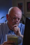 Blicke des älteren Mannes gesorgt, wie er die Lohnlisten, die on-line sind, vertikal Stockfoto
