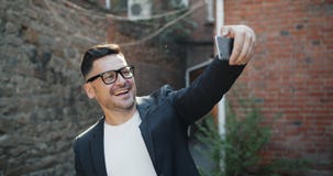 Blije mens die op middelbare leeftijd selfie met smartphonecamera die in openlucht nemen glimlachen stock video Blije mens die op middelbare leeftijd selfie met smartphonecamera die in openlucht nemen glimlachen stock video