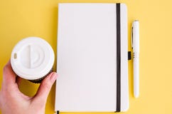 Bloc-notes blanc, stylo, tasse de café de papier dans une main femelle photographie stock Bloc-notes blanc, stylo, tasse de café de papier dans une main femelle photographie stock