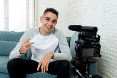 Blogger de jeune homme en ses années '20 enregistrant une vidéo sur la caméra pour des disciples sur l'Internet photographie stock Blogger de jeune homme en ses années '20 enregistrant une vidéo sur la caméra pour des disciples sur l'Internet photographie stock
