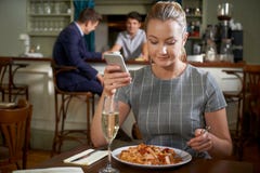 Blogger fêmea do alimento que afixa a revisão em linha da refeição Usi do restaurante fotografia de stock Blogger fêmea do alimento que afixa a revisão em linha da refeição Usi do restaurante fotografia de stock