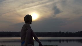 Blond jogowie siedzą w orzeł pozyci na jeziornym banku w mo zbiory Blond jogowie siedzą w orzeł pozyci na jeziornym banku w mo zbiory
