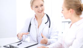 Blond kvinnlig doktor och patient som talar i sjukhuskontor Hälsovård och klientservice i medicin royaltyfri fotografi Blond kvinnlig doktor och patient som talar i sjukhuskontor Hälsovård och klientservice i medicin royaltyfri fotografi