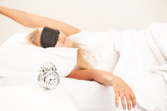 Blond woman in bed looking annoyed at her alarm clock royalty free stock image Blond woman in bed looking annoyed at her alarm clock royalty free stock image