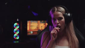 Blonde flirty gamer girl streamer puts a lollipop in her mouth