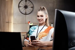 Blonde girl sitting at desk using mobilephone Stock Photos Blonde girl sitting at desk using mobilephone Stock Photos
