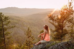 Blonde slender woman tourist in an orange t-shirt in the mountains in the summer at sunset. beautiful landscape of the Ural stock photography Blonde slender woman tourist in an orange t-shirt in the mountains in the summer at sunset. beautiful landscape of the Ural stock photography