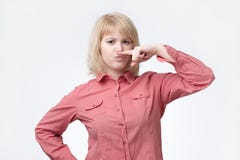 Blonde woman showing mustache with finger. She is feeling bad smell. stock photo Blonde woman showing mustache with finger. She is feeling bad smell. stock photo