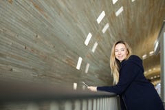Blondynka żeńskiego ucznia pozycja z nowożytnym smartphone w monophonic iluminującym tle zdjęcia stock Blondynka żeńskiego ucznia pozycja z nowożytnym smartphone w monophonic iluminującym tle zdjęcia stock