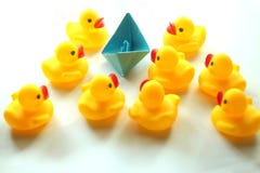 Cute yellow rubber ducks and one paper origami boat in blue color. stock photos Cute yellow rubber ducks and one paper origami boat in blue color. stock photos