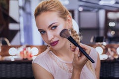 Blue-eyed woman holding face brush using powder blusher royalty free stock photo Blue-eyed woman holding face brush using powder blusher royalty free stock photo
