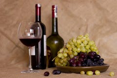Blue and green grapes on a clay brown dish. Bottle with red and royalty free stock photo Blue and green grapes on a clay brown dish. Bottle with red and royalty free stock photo