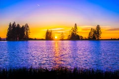 Blue and Orange Sunset over Lake With Tree Silhouettes Stock Images Blue and Orange Sunset over Lake With Tree Silhouettes Stock Images