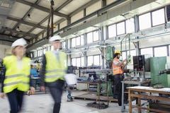 Blurred motion of business people with manual worker in background at industry royalty free stock photography Blurred motion of business people with manual worker in background at industry royalty free stock photography