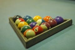 A blurred multicolored billiard balls on a blue table cloth in a wooden triangle. numbers on billiard balls royalty free stock photography A blurred multicolored billiard balls on a blue table cloth in a wooden triangle. numbers on billiard balls royalty free stock photography