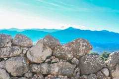 Blåa berg i det beskådade avståndet från vaggaväggarna av det forntida kullefortet av Mycenae nämnde i HomersIliad royaltyfri bild Blåa berg i det beskådade avståndet från vaggaväggarna av det forntida kullefortet av Mycenae nämnde i HomersIliad royaltyfri bild