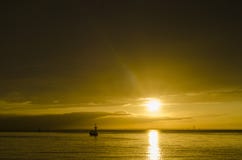 A boat under the setting sun. The golden sunset golden sky Royalty Free Stock Images A boat under the setting sun. The golden sunset golden sky Royalty Free Stock Images
