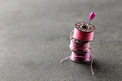 Bobbins with pink thread and a pin on a black background. stock image Bobbins with pink thread and a pin on a black background. stock image