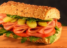 Bocadillo del primer con el jamón, el pepino conservado en vinagre, el tomate y verdes S?samo bun foto de archivo Bocadillo del primer con el jamón, el pepino conservado en vinagre, el tomate y verdes S?samo bun foto de archivo