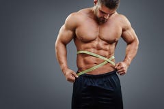 Bodybuilder die taille met meetlint meten stock foto Bodybuilder die taille met meetlint meten stock foto