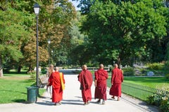 Boeddhistische monniken of priesters die in rode robe in een mooi groen park lopen stock afbeeldingen Boeddhistische monniken of priesters die in rode robe in een mooi groen park lopen stock afbeeldingen