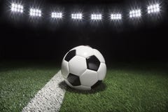 Bola de futebol tradicional no campo de grama sob luzes na noite Imagem de Stock Royalty Free Bola de futebol tradicional no campo de grama sob luzes na noite Imagem de Stock Royalty Free